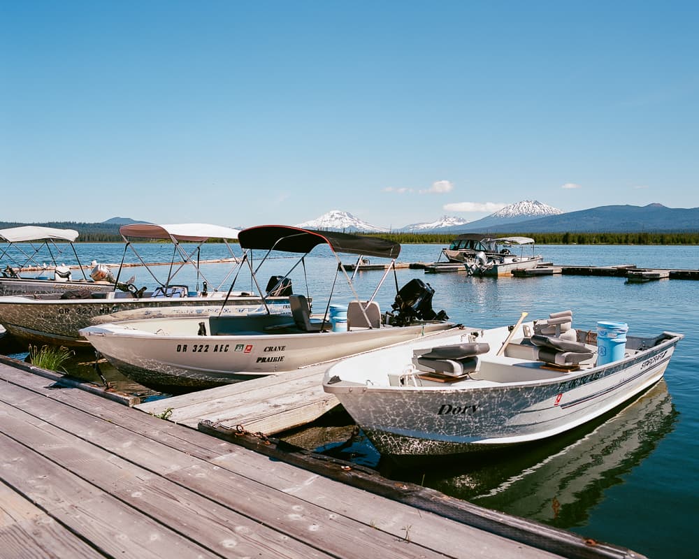 Aluminum fishing boats moored at a wooden dock with snow-capped Cascade peaks in the distance